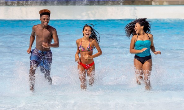 Three friends running through water in pool