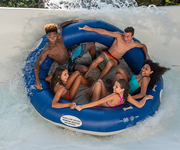 Teenagers in tube on waterslide, laughing.